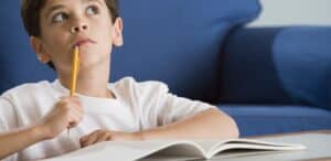Bambino che pensa prima di scrivere a mano
