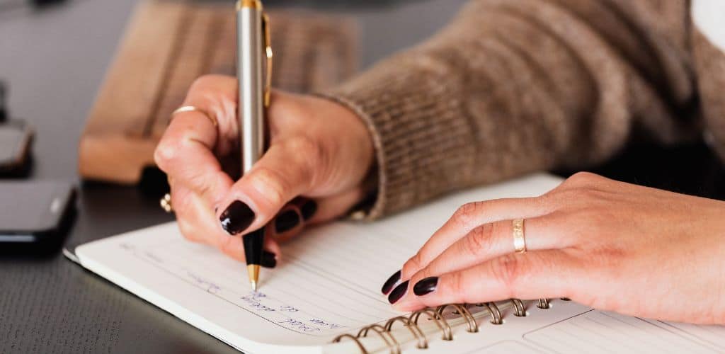 Persona che scrive con la penna sull'agenda i suoi impegni