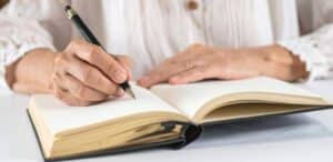 Persona che scrive con la sua penna su un taccuino
