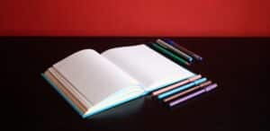 Taccuino aperto su un tavolo con dei pennarelli affianco